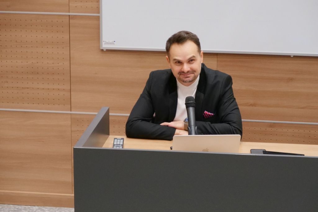 dr Daniel Wolder w auli przy biurku siedzi